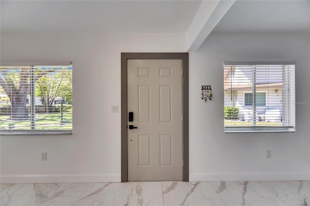 entrance foyer featuring marble finish floor and baseboards