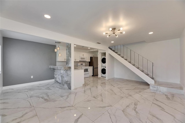 unfurnished living room with marble finish floor, baseboards, stairway, and stacked washing maching and dryer