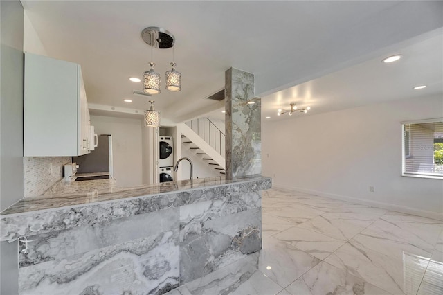 kitchen featuring marble finish floor, stacked washer / drying machine, recessed lighting, white cabinets, and baseboards