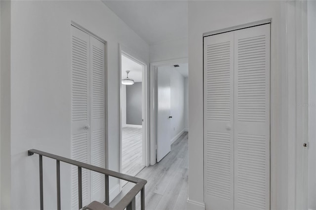 corridor with light wood-type flooring and baseboards