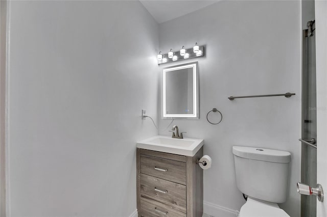 bathroom featuring baseboards, vanity, and toilet