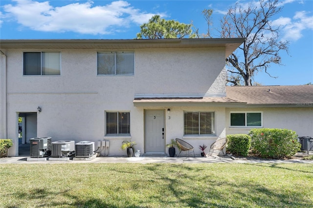 view of front of property featuring central AC unit, a front yard, and stucco siding