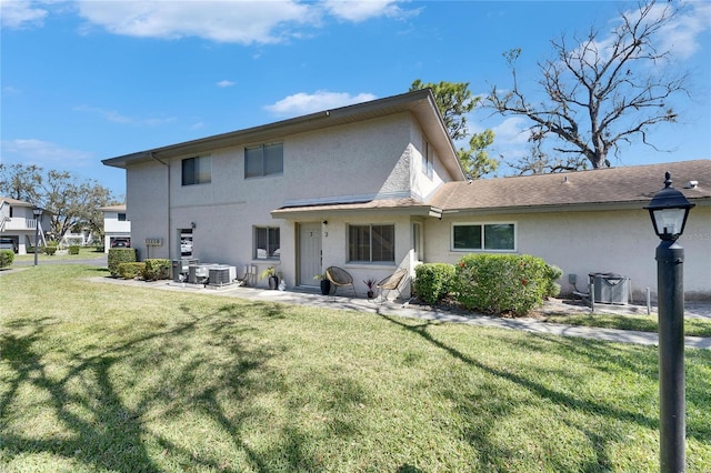 back of property with a yard, central AC unit, a patio, and stucco siding