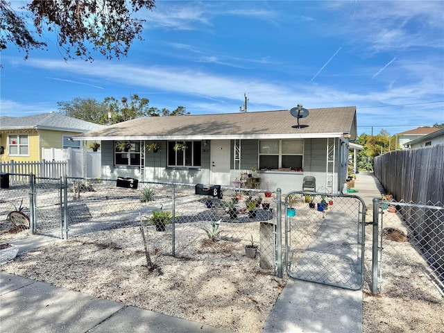 ranch-style home featuring a fenced front yard, a gate, and covered porch