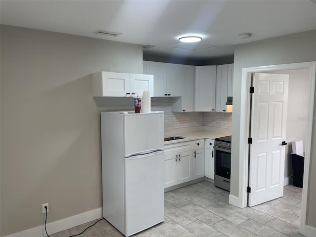 kitchen featuring freestanding refrigerator, tasteful backsplash, electric range, white cabinetry, and light countertops