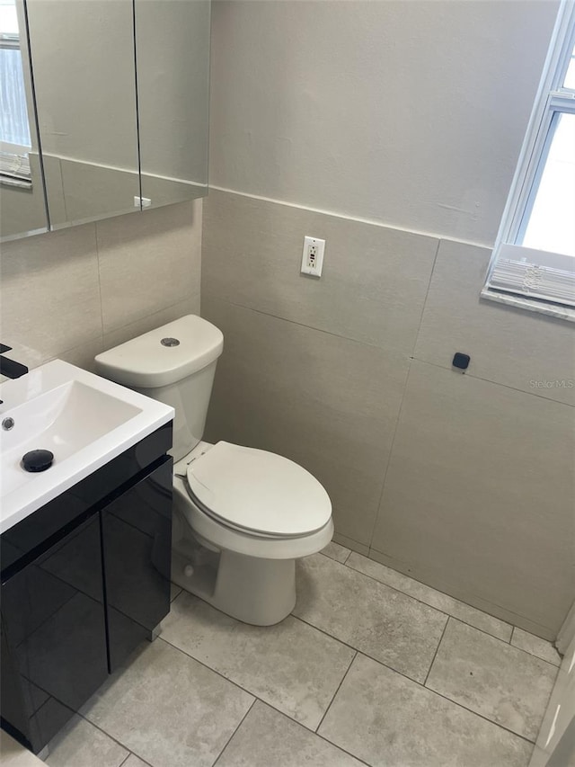 half bath with tile patterned flooring, vanity, and toilet