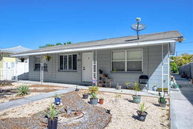view of front of property featuring fence and a shingled roof
