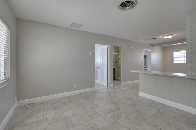 empty room featuring visible vents, baseboards, and light tile patterned floors