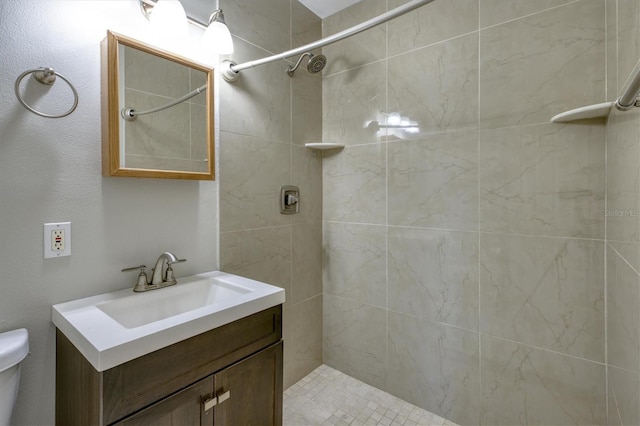 full bathroom with tiled shower, vanity, and toilet