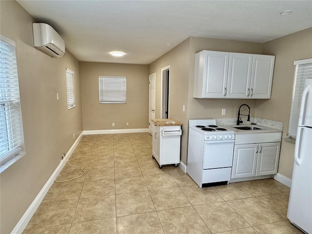 kitchen with white appliances, a wall unit AC, white cabinets, light countertops, and a sink