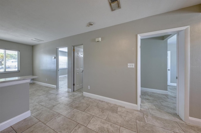 spare room featuring visible vents, baseboards, and light tile patterned floors