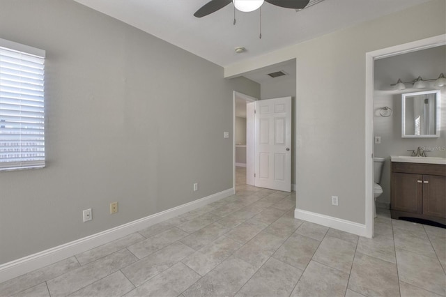 unfurnished bedroom featuring baseboards, light tile patterned floors, ensuite bathroom, visible vents, and a sink