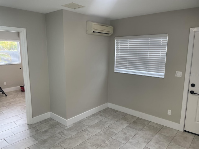spare room featuring light tile patterned floors, baseboards, and a wall unit AC