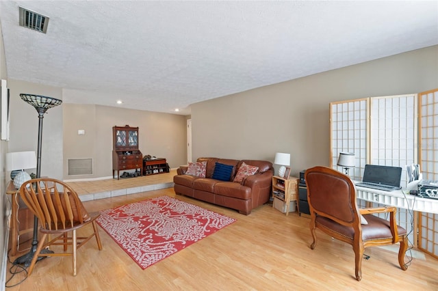 living room with a textured ceiling, visible vents, wood finished floors, and recessed lighting