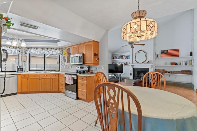 kitchen featuring visible vents, a fireplace with raised hearth, a tray ceiling, stainless steel appliances, and a sink