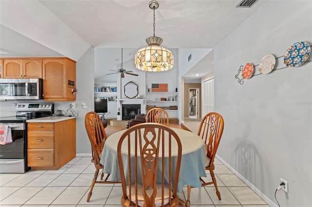 dining space featuring a fireplace with raised hearth, ceiling fan, light tile patterned floors, lofted ceiling, and visible vents