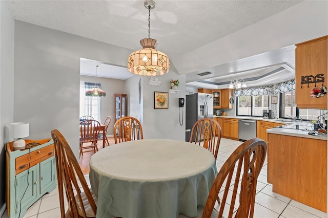 dining space featuring a textured ceiling, light tile patterned flooring, and a raised ceiling