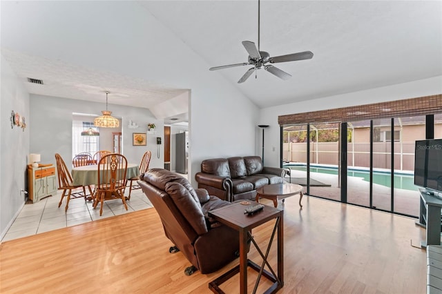 living room with light wood-type flooring, high vaulted ceiling, visible vents, and a ceiling fan