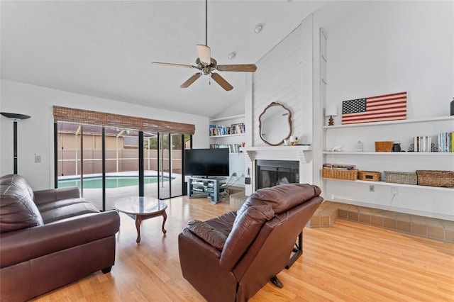 living room with ceiling fan, a fireplace, high vaulted ceiling, and wood finished floors