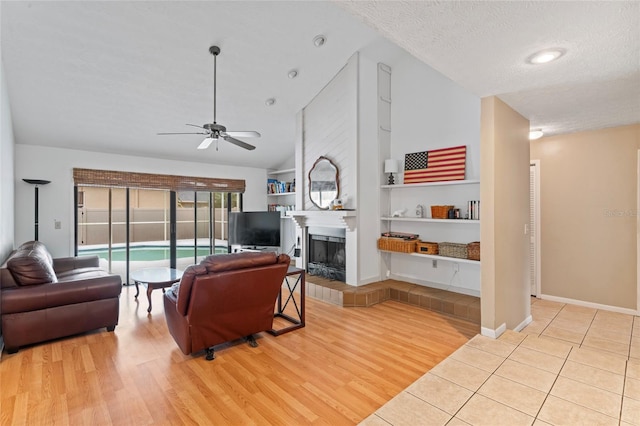 living room featuring built in features, a fireplace, vaulted ceiling, a textured ceiling, and wood finished floors