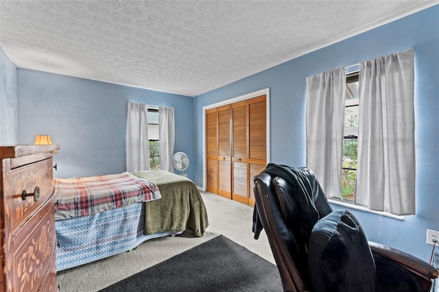 bedroom with a closet, carpet flooring, a textured ceiling, and multiple windows