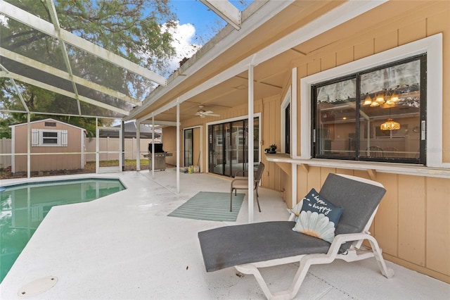 view of swimming pool with a patio, glass enclosure, fence, a shed, and an outdoor structure