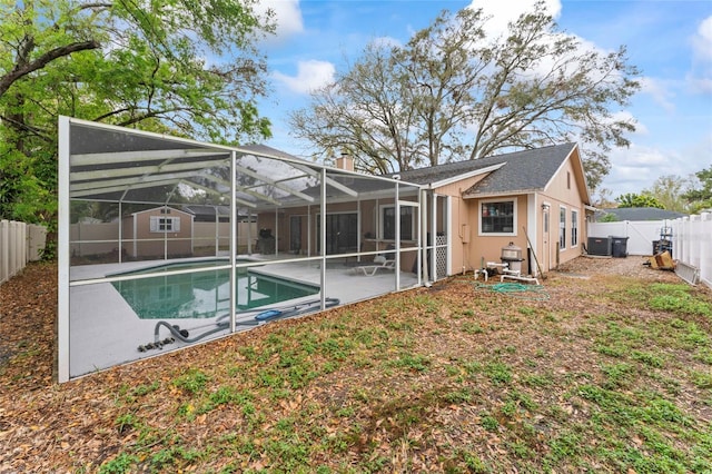 back of house featuring a patio area, a fenced backyard, glass enclosure, and a fenced in pool