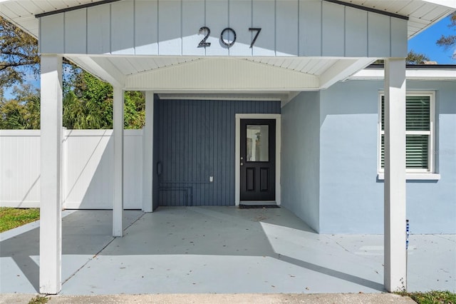 doorway to property featuring board and batten siding and fence