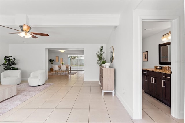 interior space featuring beam ceiling, ceiling fan, baseboards, and light tile patterned floors