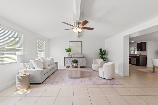 living room with lofted ceiling, ceiling fan, light tile patterned flooring, and baseboards