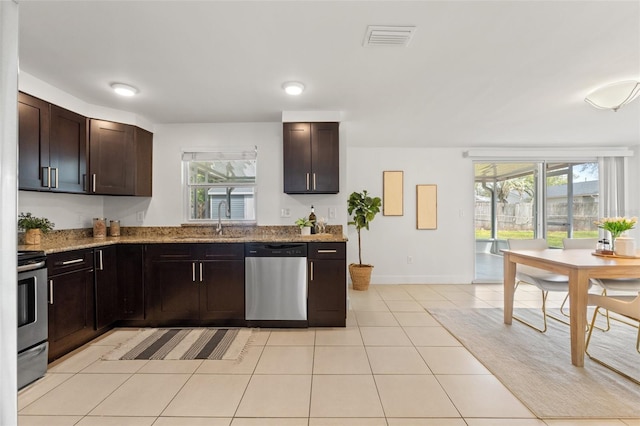 kitchen with light tile patterned floors, a sink, visible vents, stainless steel dishwasher, and range