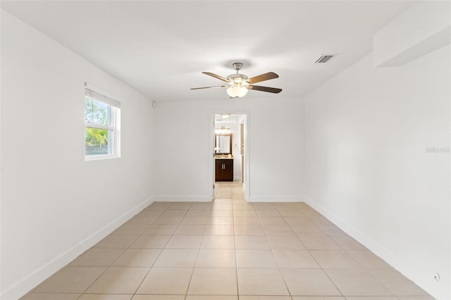 spare room featuring light tile patterned floors, baseboards, visible vents, and ceiling fan