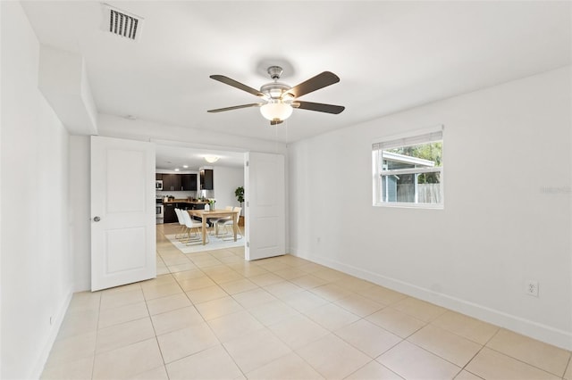 empty room with visible vents, ceiling fan, baseboards, and light tile patterned floors