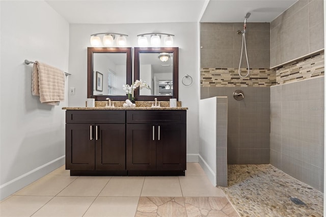 bathroom featuring double vanity, baseboards, tile patterned flooring, a walk in shower, and a sink