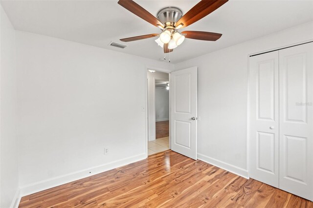 unfurnished bedroom featuring baseboards, light wood-style flooring, visible vents, and a closet