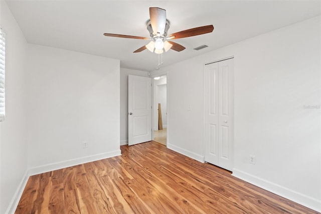 unfurnished room featuring light wood-style floors, baseboards, visible vents, and a ceiling fan