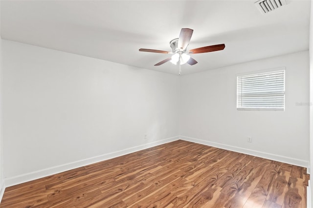 empty room with a ceiling fan, visible vents, baseboards, and wood finished floors