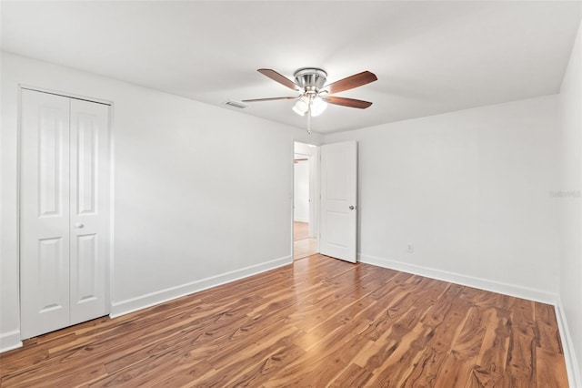 unfurnished bedroom featuring a closet, wood finished floors, visible vents, and baseboards