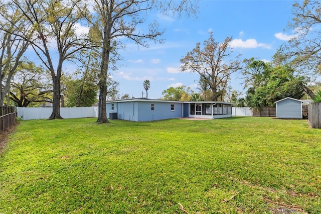 view of yard with a sunroom, a fenced backyard, an outdoor structure, and a shed