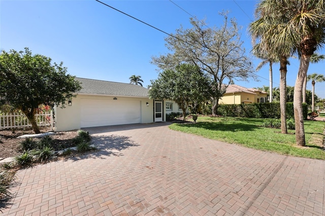 ranch-style house with a front lawn, decorative driveway, an attached garage, and stucco siding