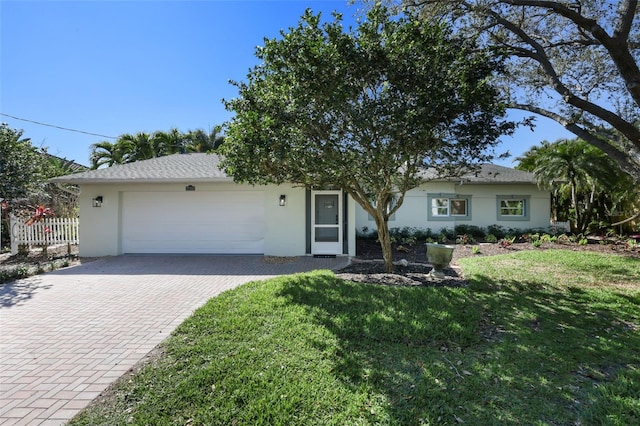 ranch-style house with a front lawn, decorative driveway, an attached garage, and stucco siding