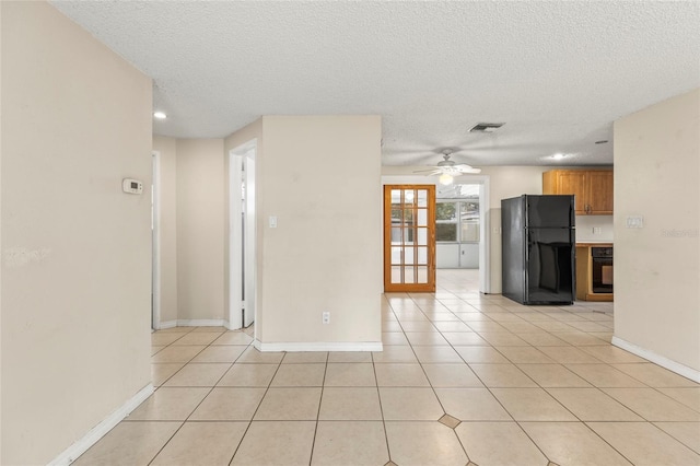 spare room featuring light tile patterned floors, visible vents, ceiling fan, a textured ceiling, and baseboards