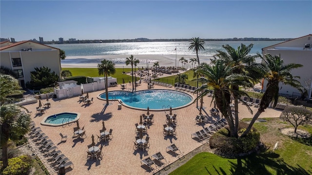 pool with a water view, fence, and a patio