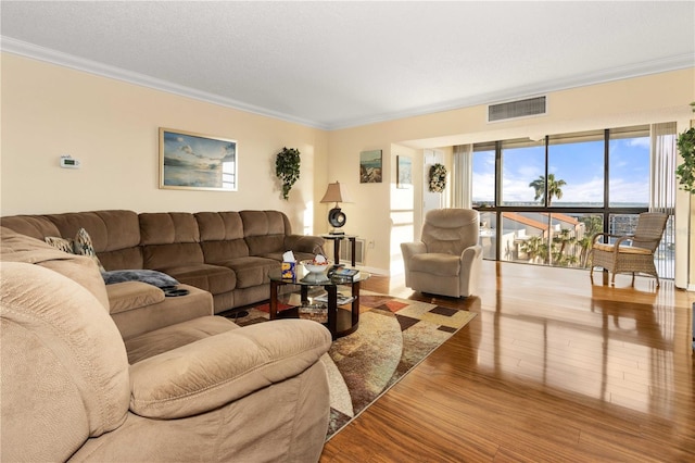 living area featuring wood finished floors, visible vents, and crown molding