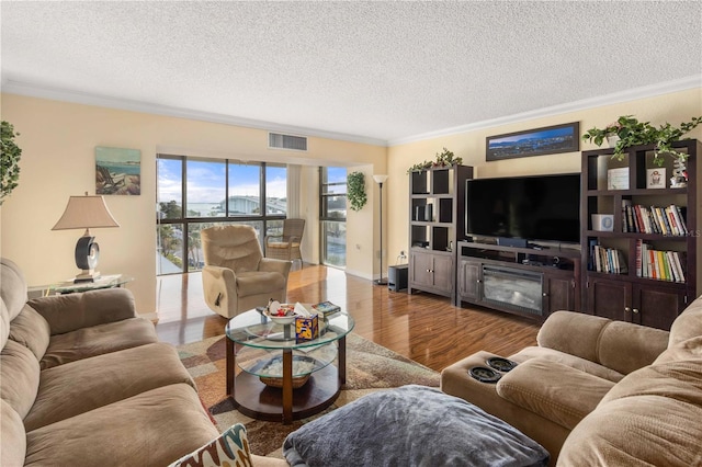 living area featuring crown molding, a textured ceiling, visible vents, and wood finished floors