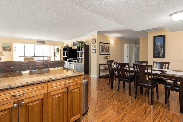 interior space featuring visible vents, brown cabinets, wood finished floors, crown molding, and a textured ceiling