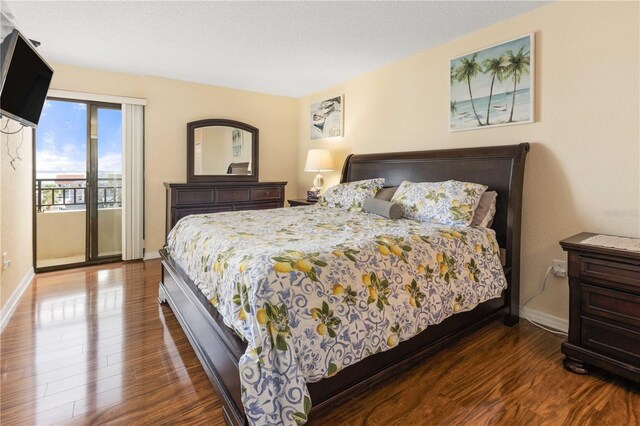 bedroom featuring access to outside, a textured ceiling, baseboards, and wood finished floors