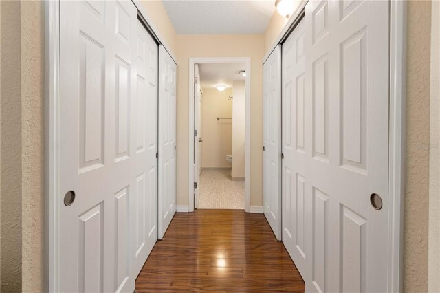 hall with baseboards and dark wood-type flooring