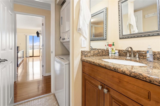 bathroom with tile patterned floors, vanity, stacked washer and clothes dryer, and crown molding