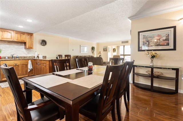 dining room featuring a textured ceiling, dark wood-type flooring, baseboards, and crown molding